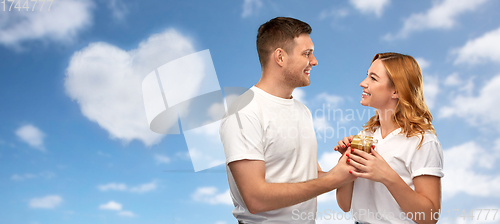 Image of happy couple in white t-shirts with gift