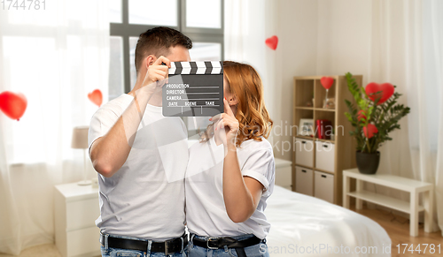 Image of happy couple in white t-shirts with clapperboard