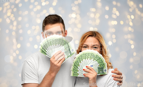 Image of happy couple in white t-shirts with euro money