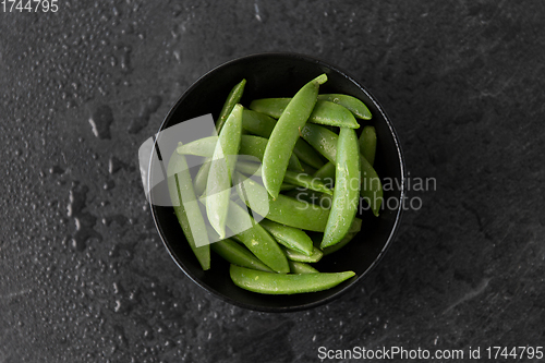 Image of peas in bowl on wet slate stone background