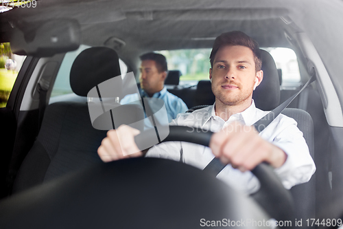 Image of male driver with wireless earphones driving car