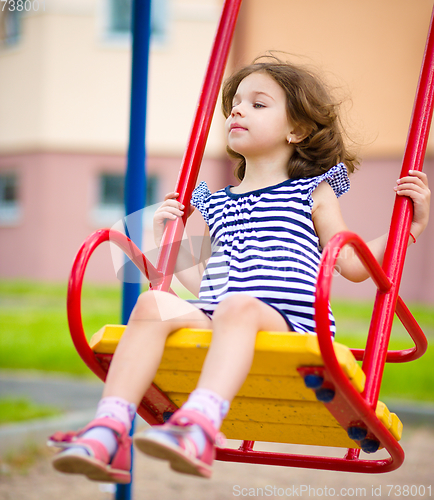 Image of Young girl is swinging in playground