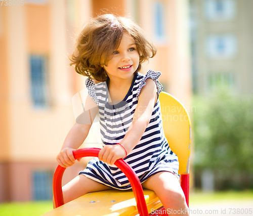 Image of Young happy girl is swinging in playground