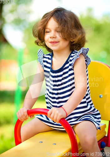 Image of Young happy girl is swinging in playground