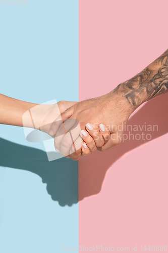 Image of Closeup shot of human holding hands isolated on yellow studio background.