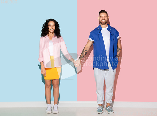 Image of Young emotional man and woman on pink and blue background