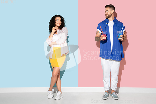 Image of Young emotional man and woman on pink and blue background