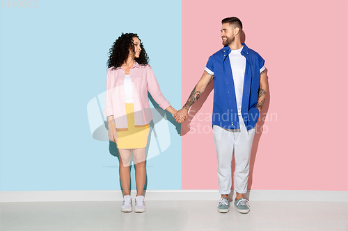Image of Young emotional man and woman on pink and blue background