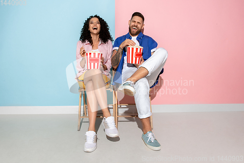 Image of Young emotional man and woman on pink and blue background