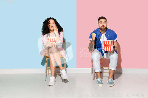 Image of Young emotional man and woman on pink and blue background