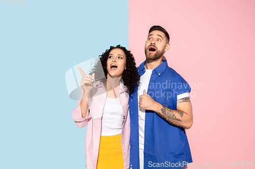 Image of Young emotional man and woman on pink and blue background