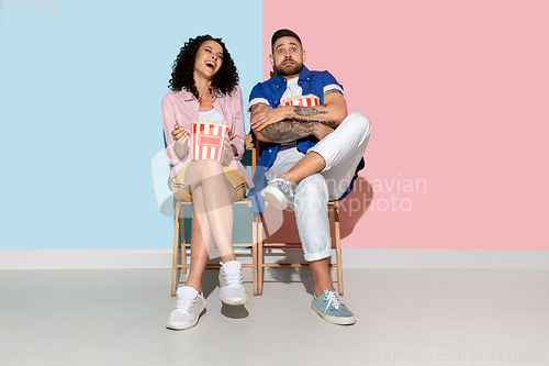 Image of Young emotional man and woman on pink and blue background