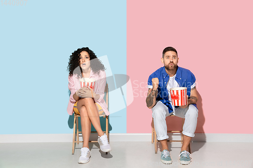 Image of Young emotional man and woman on pink and blue background
