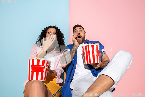 Image of Young emotional man and woman on pink and blue background