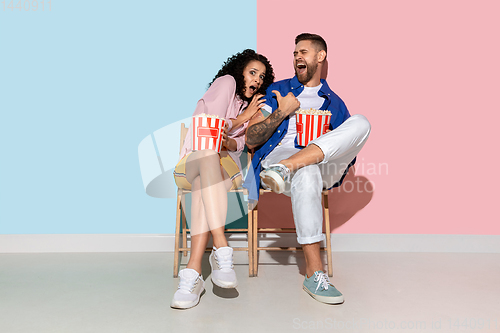 Image of Young emotional man and woman on pink and blue background