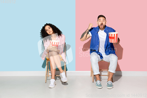 Image of Young emotional man and woman on pink and blue background