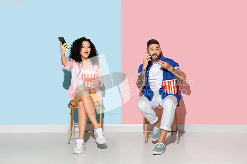 Image of Young emotional man and woman on pink and blue background