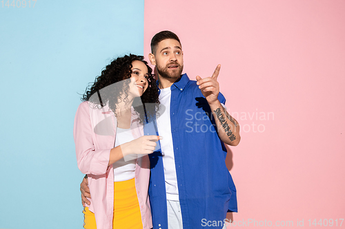 Image of Young emotional man and woman on pink and blue background