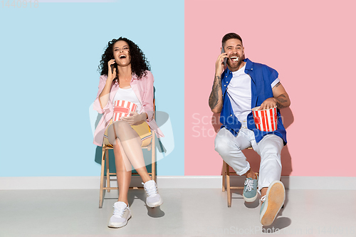 Image of Young emotional man and woman on pink and blue background