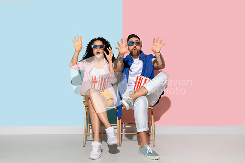 Image of Young emotional man and woman on pink and blue background
