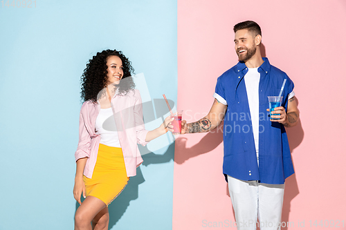 Image of Young emotional man and woman on pink and blue background
