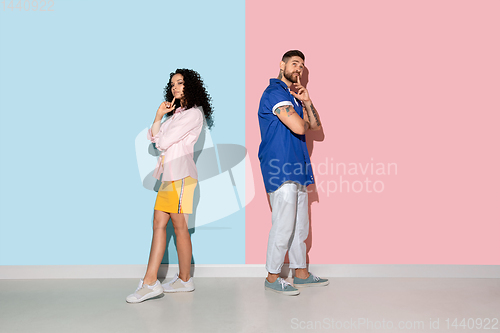 Image of Young emotional man and woman on pink and blue background