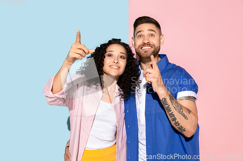 Image of Young emotional man and woman on pink and blue background
