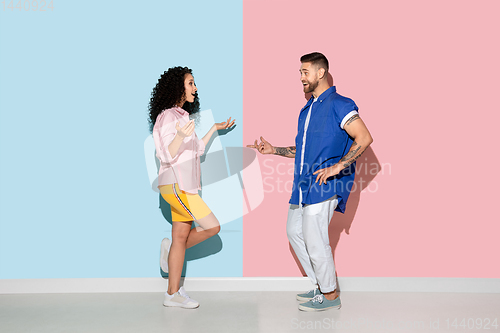 Image of Young emotional man and woman on pink and blue background