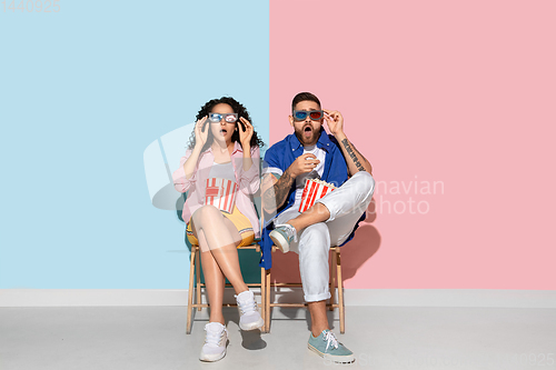 Image of Young emotional man and woman on pink and blue background