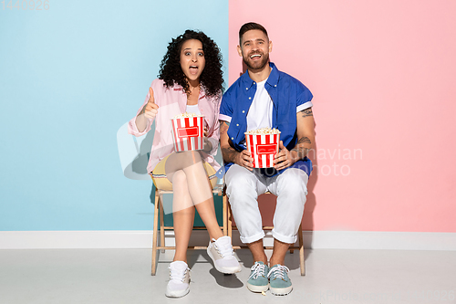 Image of Young emotional man and woman on pink and blue background