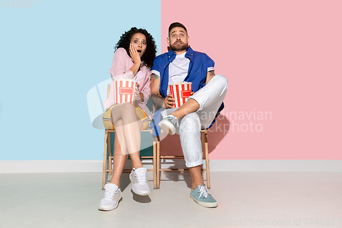 Image of Young emotional man and woman on pink and blue background