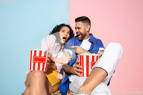 Image of Young emotional man and woman on pink and blue background