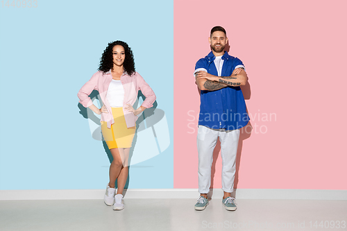Image of Young emotional man and woman on pink and blue background
