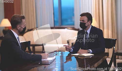 Image of business people wearing crona virus protection face mask on meeting