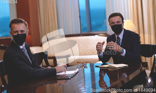 Image of business people wearing crona virus protection face mask on meeting