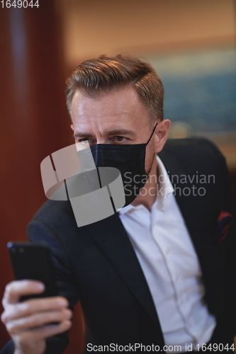 Image of business man using smart phone at luxury office wearing face mask