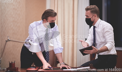 Image of business people wearing crona virus protection face mask on meeting