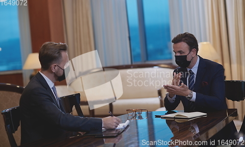 Image of business people wearing crona virus protection face mask on meeting