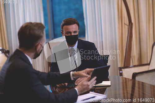 Image of business people wearing crona virus protection face mask on meeting