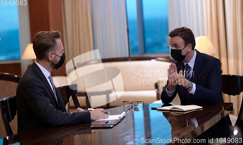 Image of business people wearing crona virus protection face mask on meeting