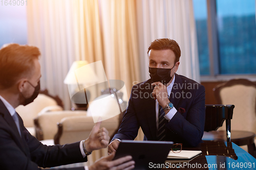 Image of business people wearing crona virus protection face mask on meeting