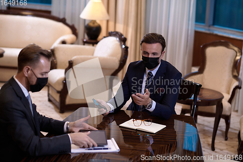 Image of business people wearing crona virus protection face mask on meeting