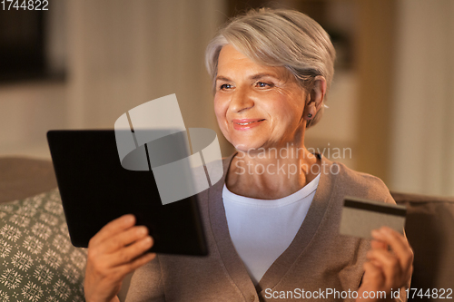 Image of old woman with tablet pc and credit card at home