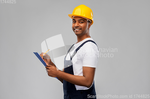 Image of happy builder in helmet with clipboard and pencil