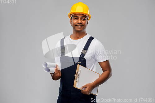 Image of happy indian builder with blueprint and clipboard