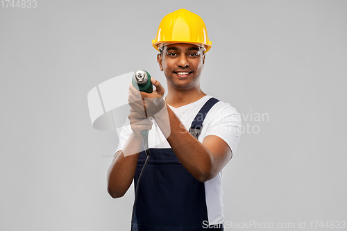 Image of happy indian builder in helmet with electric drill