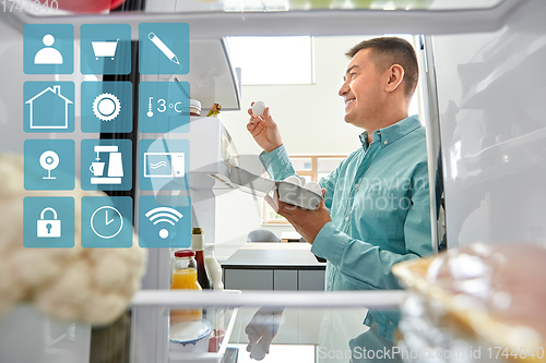 Image of man taking eggs from fridge at kitchen