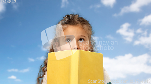 Image of little girl hiding behind yellow book