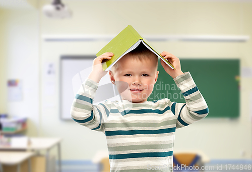 Image of smiling boy with book on head at school