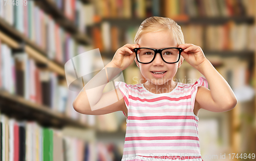 Image of smiling little girl in black glasses at library